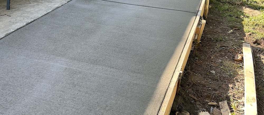 Finished concrete walkway and front approach leading toward a home.
