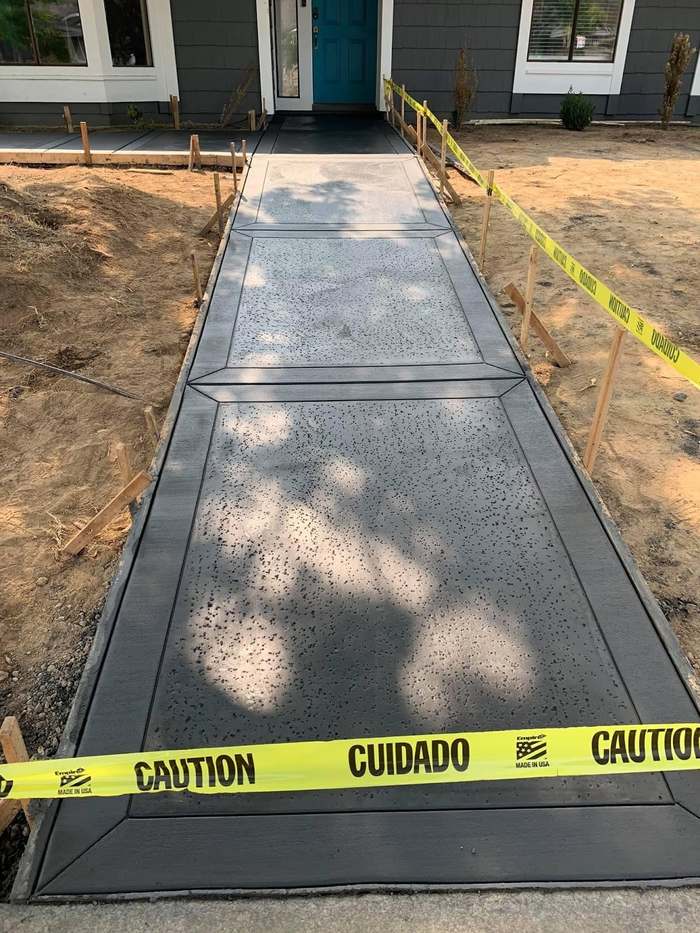Dark stamped concrete walkway leading toward a front door.